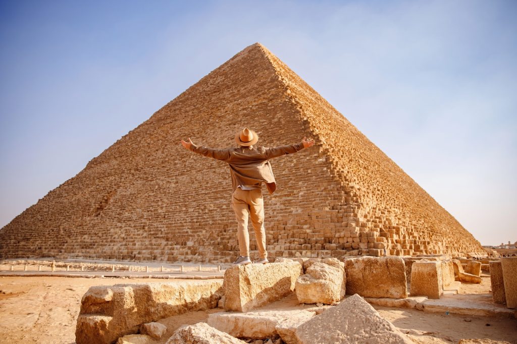 Travel man in hat stand background Egyptian pyramid sunset Giza Cairo, Egypt.