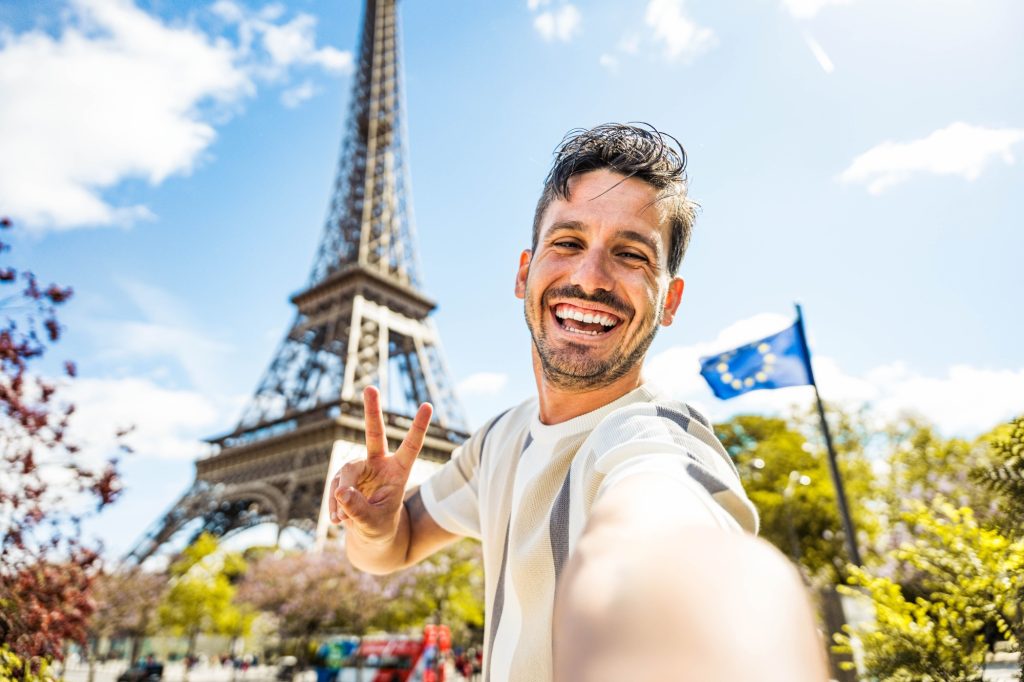 Happy tourist taking selfie picture in front of Eiffel Tower in Paris, France - Travel and summer vacation life style concept
