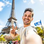 Happy tourist taking selfie picture in front of Eiffel Tower in Paris, France - Travel and summer vacation life style concept