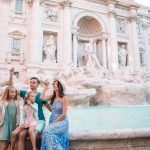 Travel family trowing coin at Trevi Fountain, Rome, Italy for good luck. Happy young parents and little kids smiling traveling together on european travel vacation holiday in Europe.