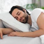 Healthy sleep concept. Closeup of handsome bearded young man sleeping in nice comfortable bed at home, enjoying good sleep