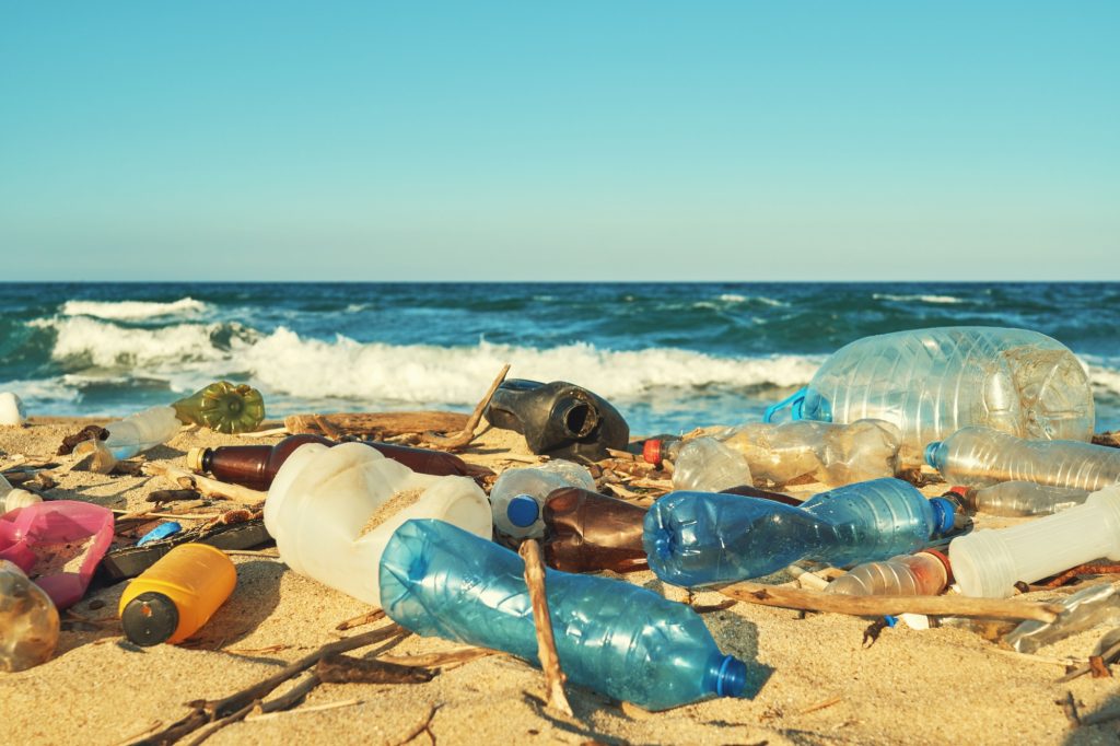 Spilled garbage on the beach of the big city. Empty used dirty plastic bottles. Dirty sea sandy shore the Black Sea. Environmental pollution. Ecological problem. Moving waves in the background