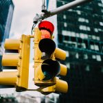 Equipment for regulating transport with lambs hanging in downtown in usa,yellow traffic lights controlling cars and supporting safety on crossways in megalopolis with high buildings and construction