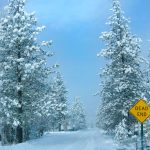 Bright yellow traffic sign signals the end of a snow covered road. Yellow dead end sign sticks out in the idyllic wintry scenery. Empty road runs across the snowy countryside.
