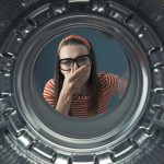 Disgusted woman looking into her smelly washing machine, she is holding her nose, point of view shot