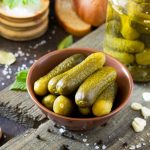 Marinated cucumbers gherkins. Pickles with mustard and garlic on a stone background.