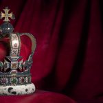 Royal golden crown with jewels on pillow on pink red background. Symbols of UK United Kingdom monarchy. 3d illustration