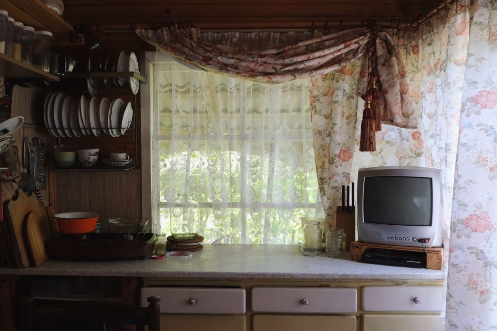 Rustic wooden kitchen interior with retro TV set on the counter. Cute cottage kitchen interior design