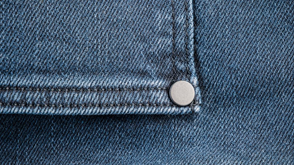 Close-up view of denim fabric with silver rivet detail