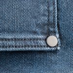 Close-up view of denim fabric with silver rivet detail