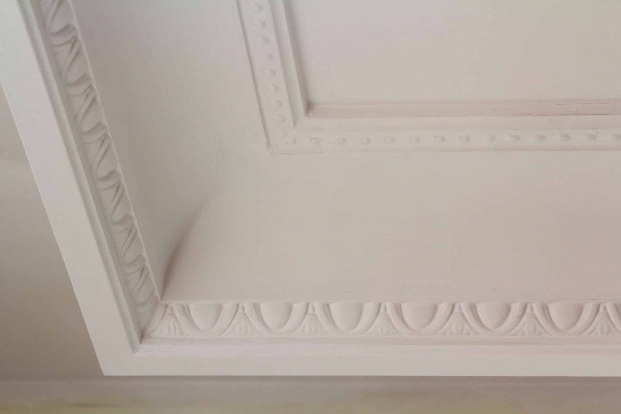 Ornamental white molding decor on ceiling of white room close-up detail. Interior renovation and construction concept.