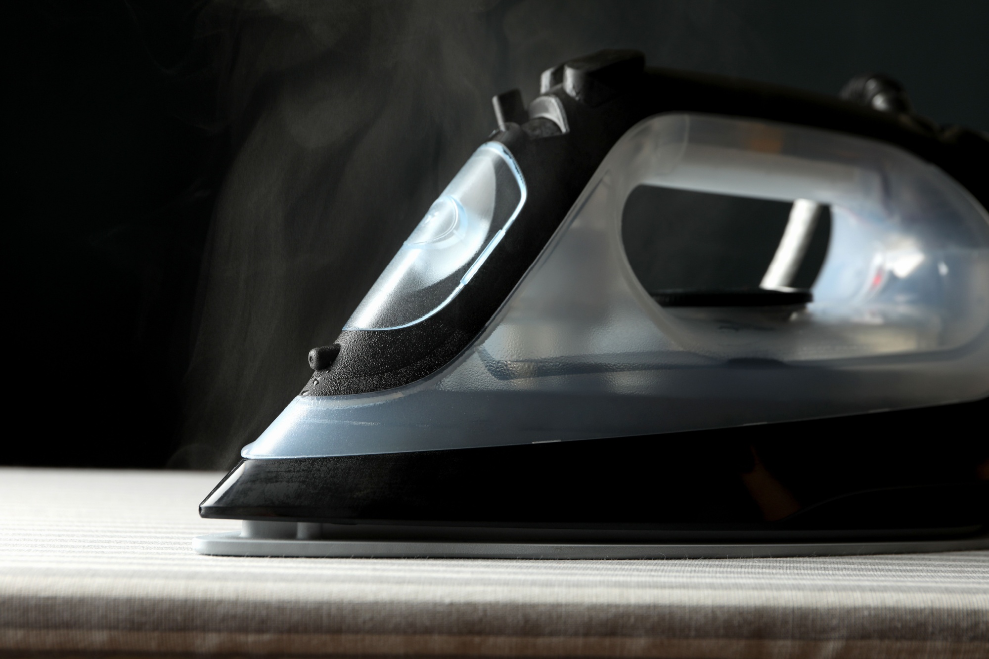 Iron with steam on ironing board, close up