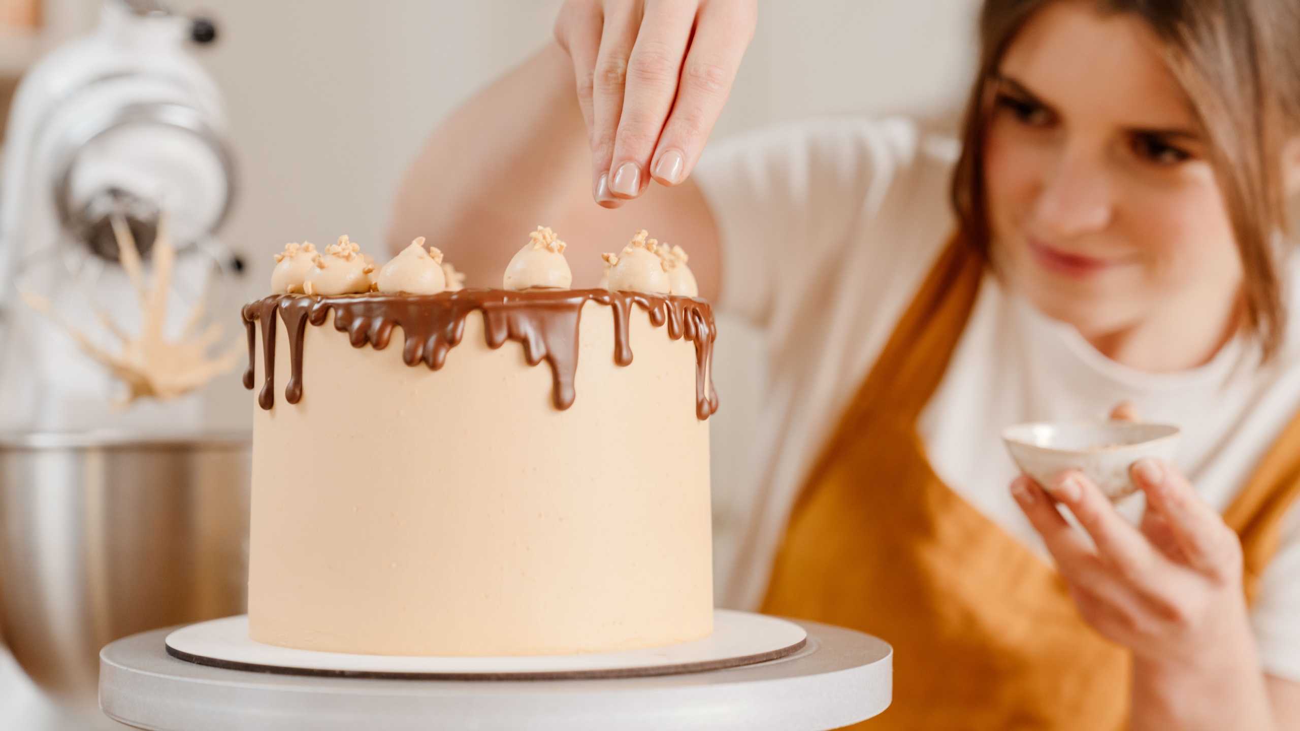 Beautiful focused pastry chef woman making cake with chocolate cream at cozy kitchen