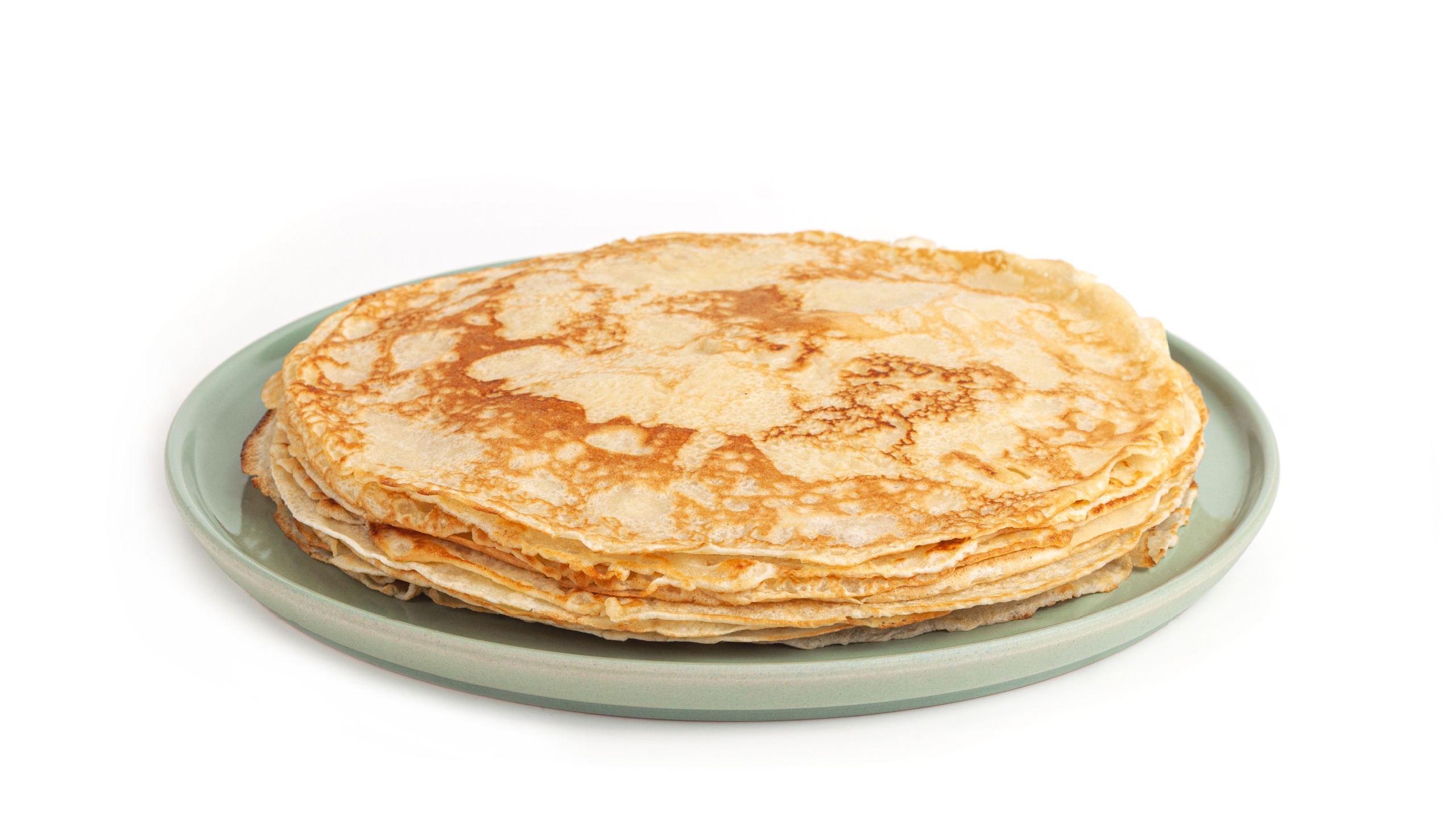 Pancake on green plate on white background. Many pancakes are stacked. Thin pancakes with crispy crust. Maslenitsa. Pancakes for breakfast and carnival. Food background.