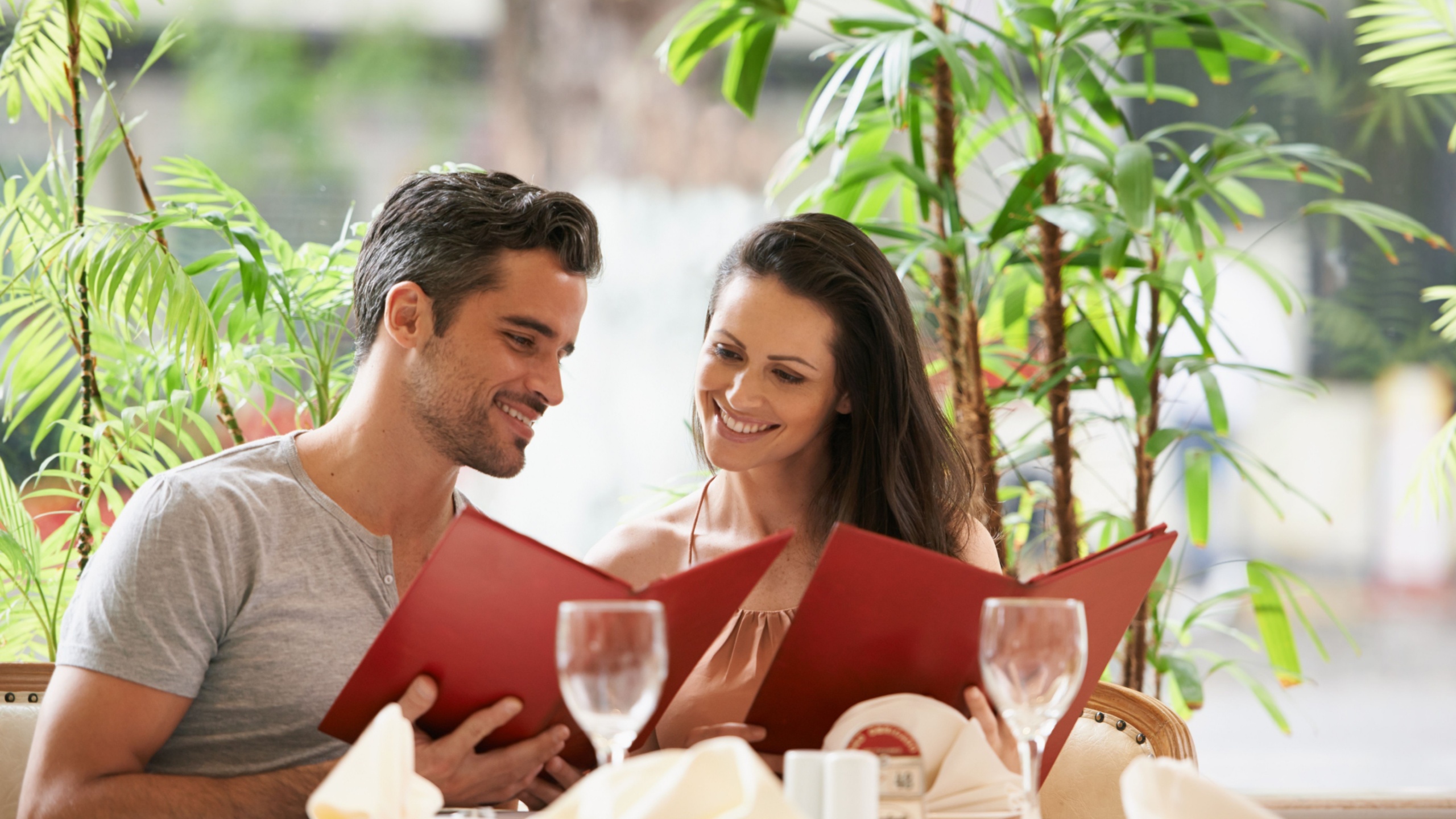 Couple, restaurant and reading a menu on date, fine dining and bonding on valentines day. People, love and romance at cafe or lunch choice for anniversary celebration, cuisine and happy at bistro