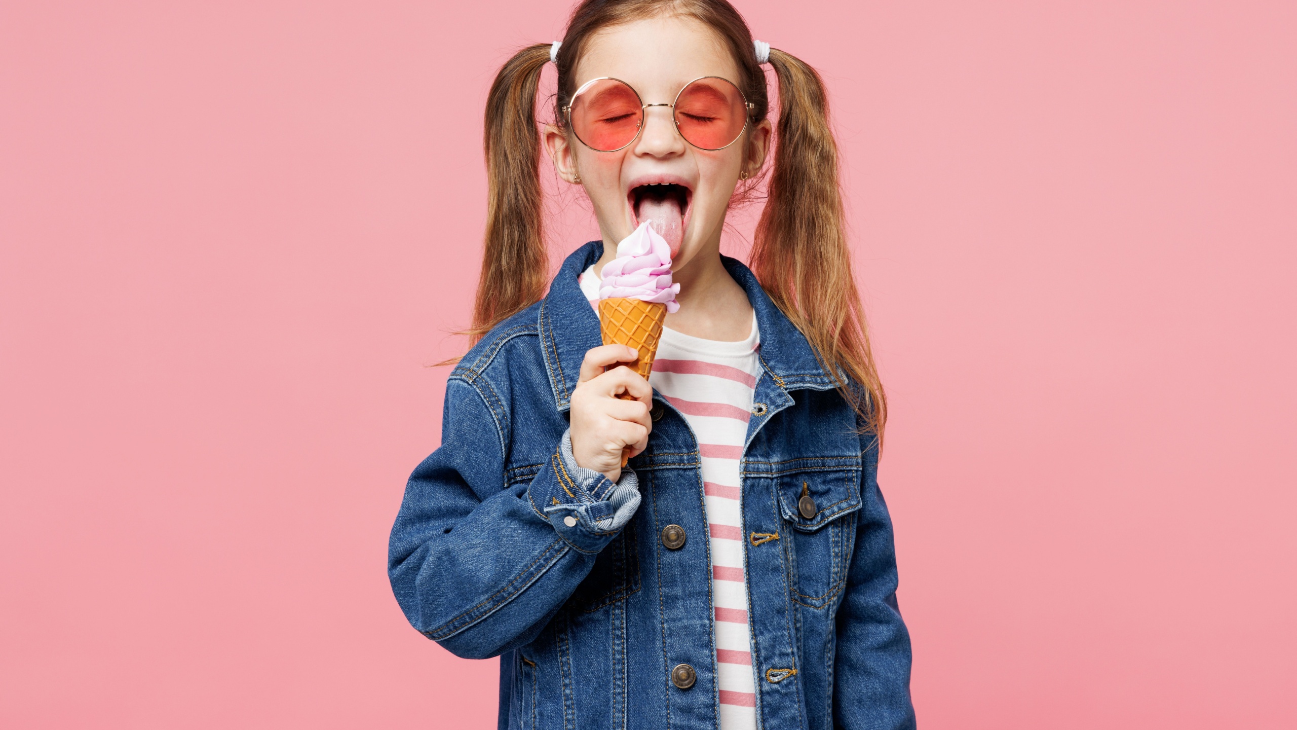 Little child smiling cute kid girl 7-8 years old wears denim shirt glasses have fun eat ice cream close eyes isolated on plain pastel light pink background. Mother's Day love family lifestyle concept