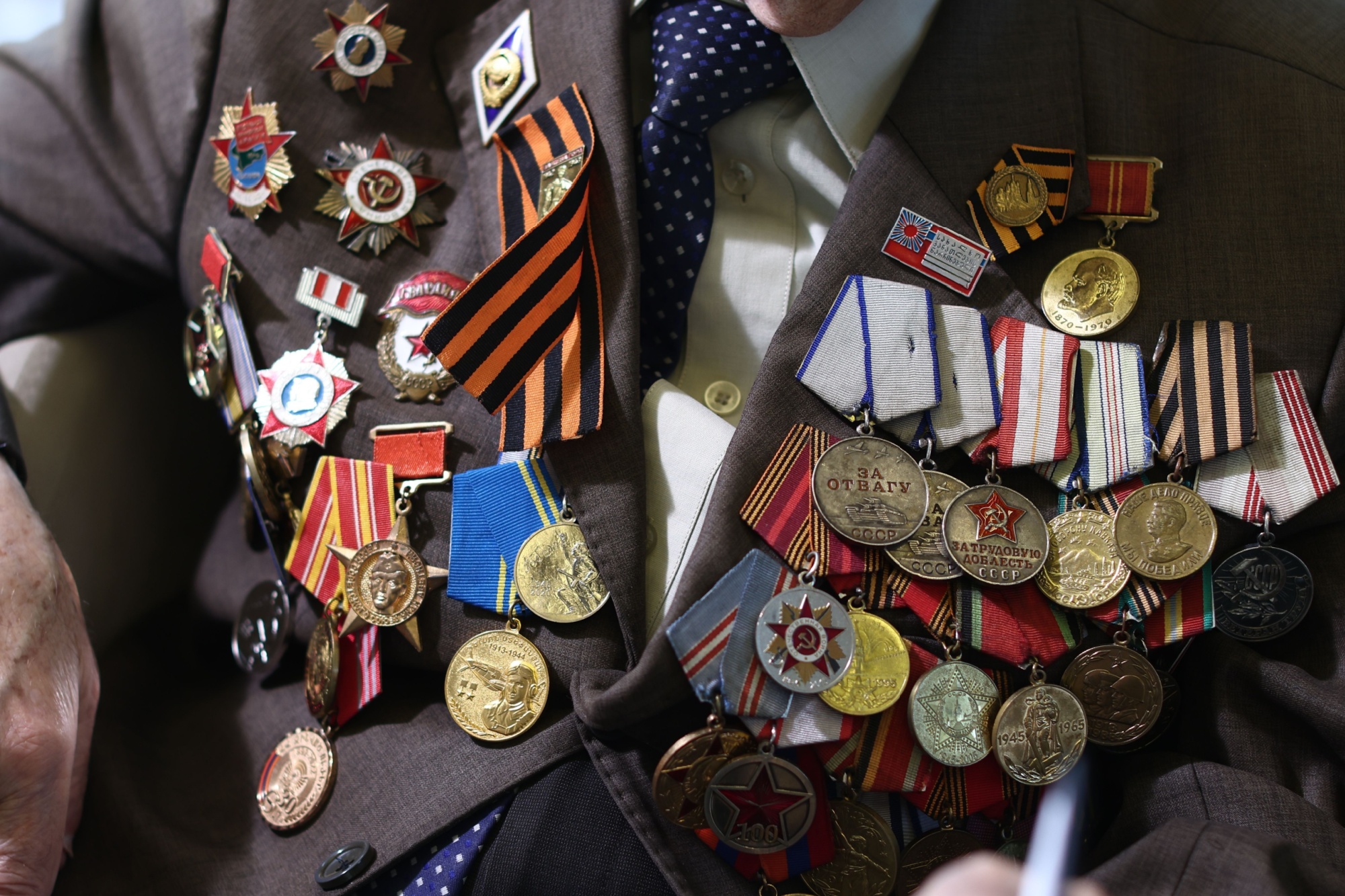Close-up of a veteran's jacket adorned with numerous military medals and ribbons, symbolizing honor and bravery.