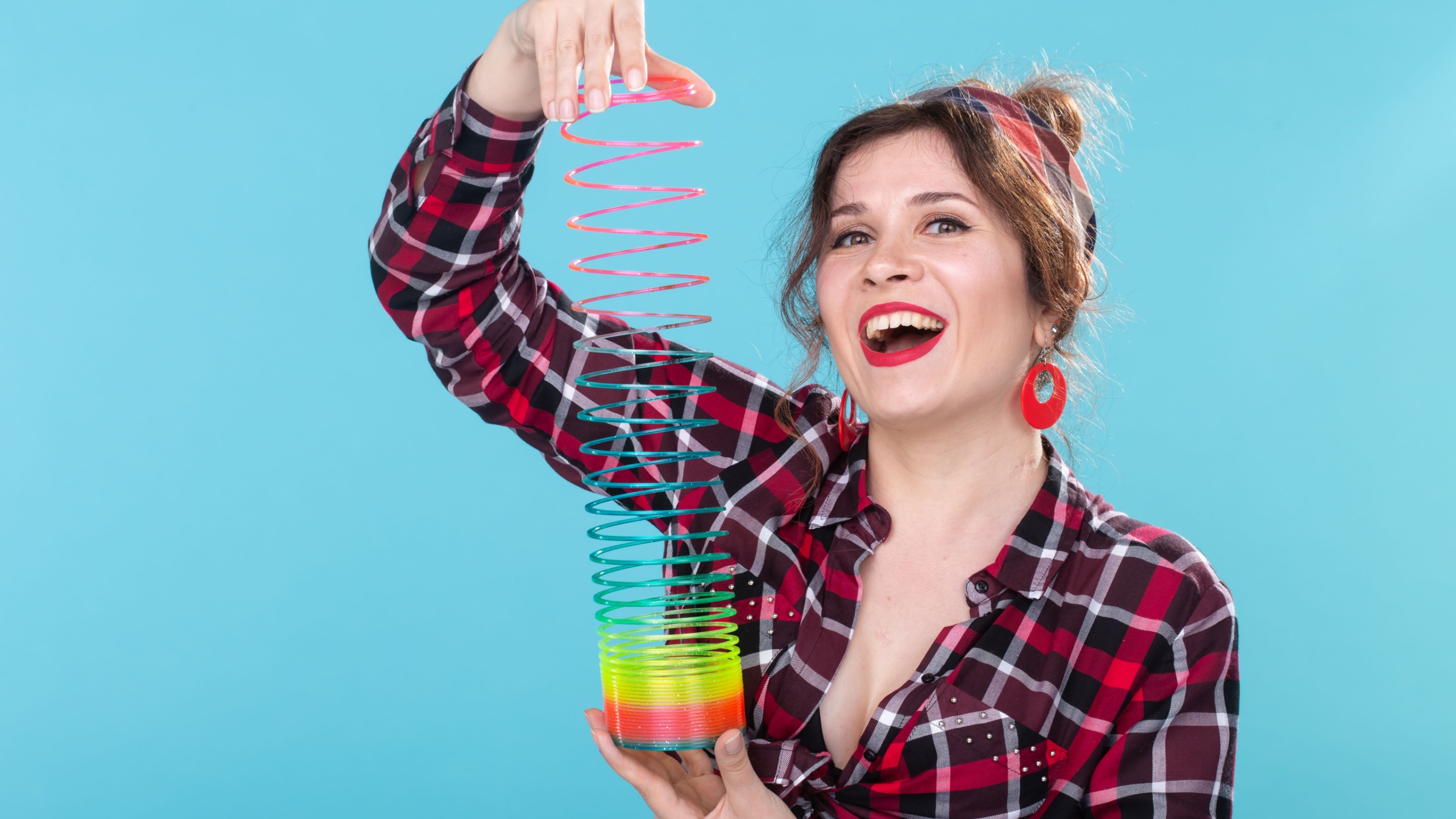 UFA, RUSSIA - APRIL 2, 2019 : pin-up woman playing with a slinky on blue backgroud