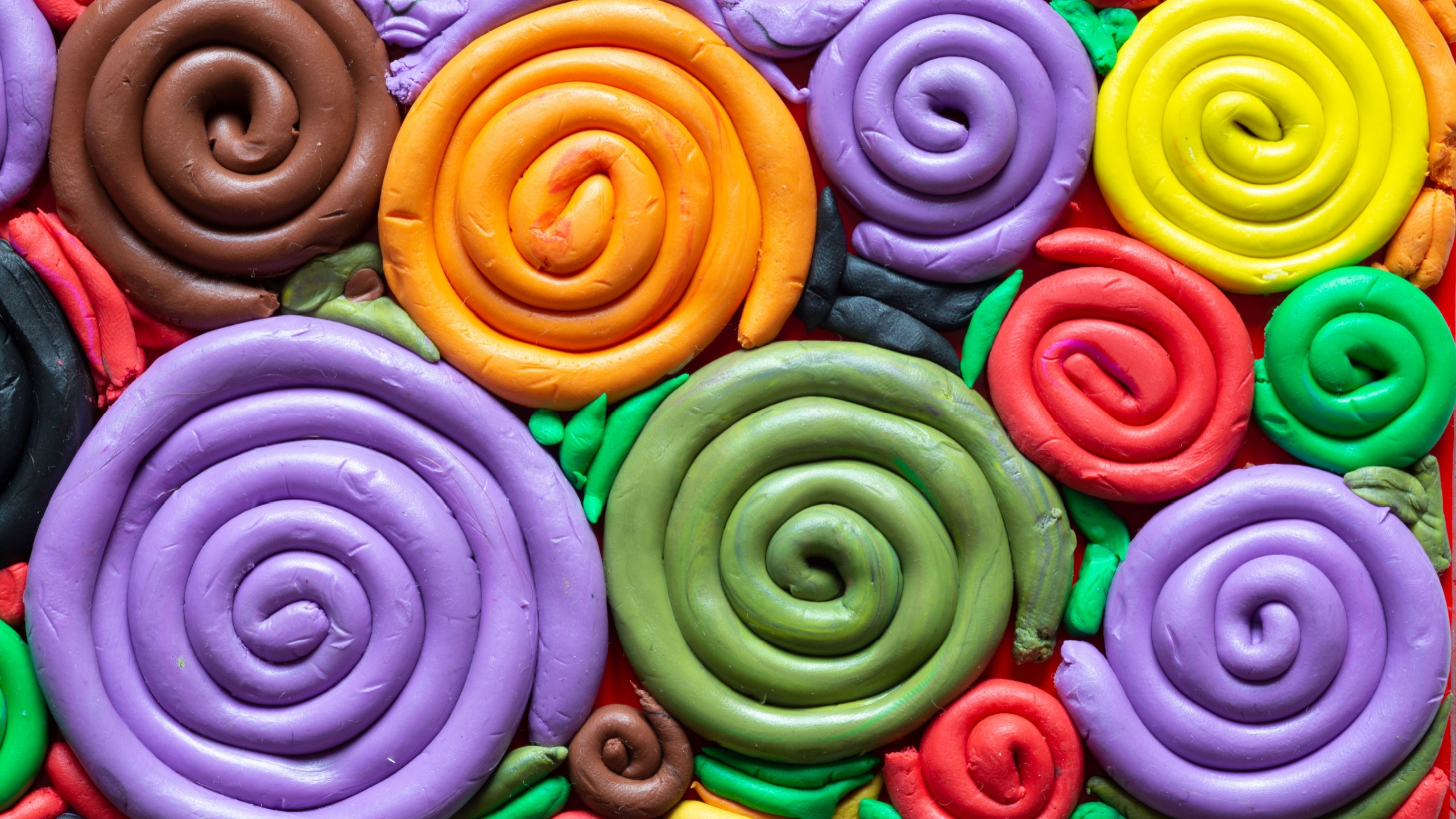 Color spectrum made of play dough - coil-shaped colorful artistic creation - children's creativity. Spiral snail shells made of doh.