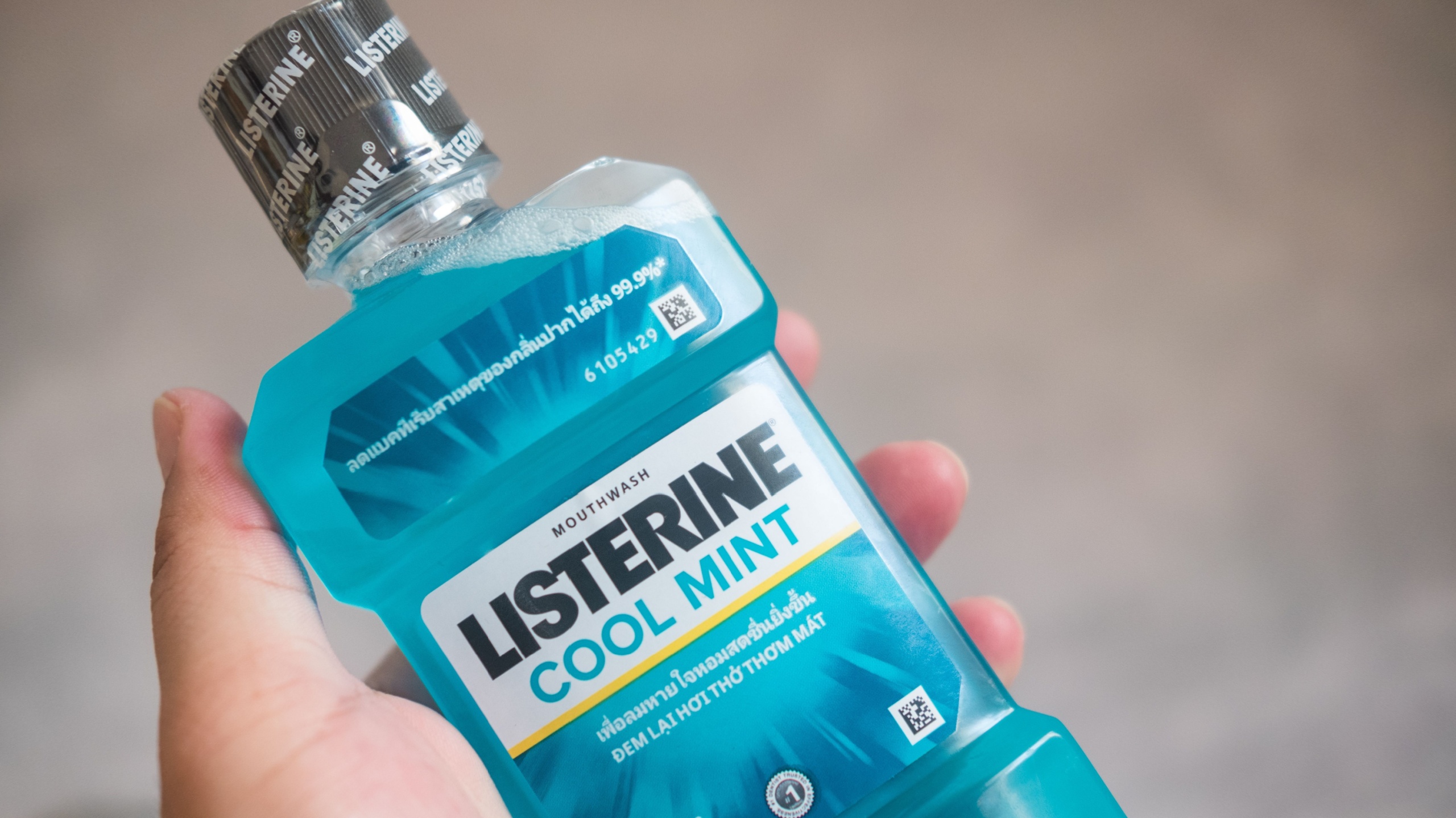 Samut Prakan, Thailand - March 22, 2022 : Man's hand is holding Listerine mouthwash bottle. Listerine is a brand of antiseptic mouthwash product.