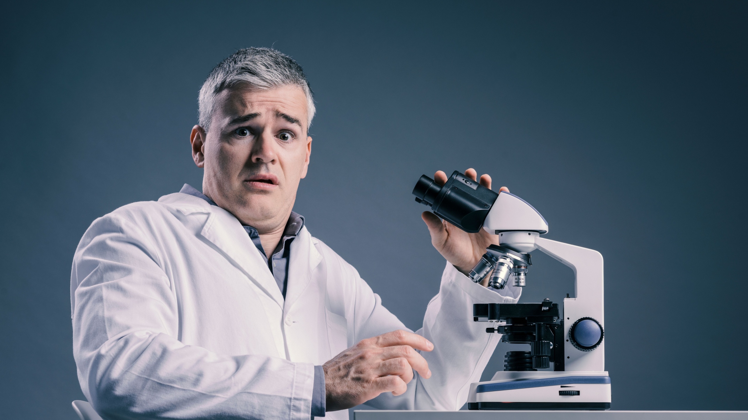 Funny shocked medical scientist working with a microscope, he made an incredible discovery