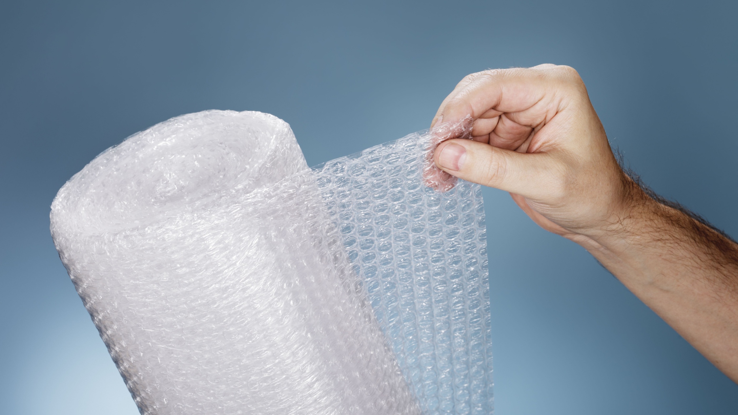 Man holding a roll of plastic bubble wrap.