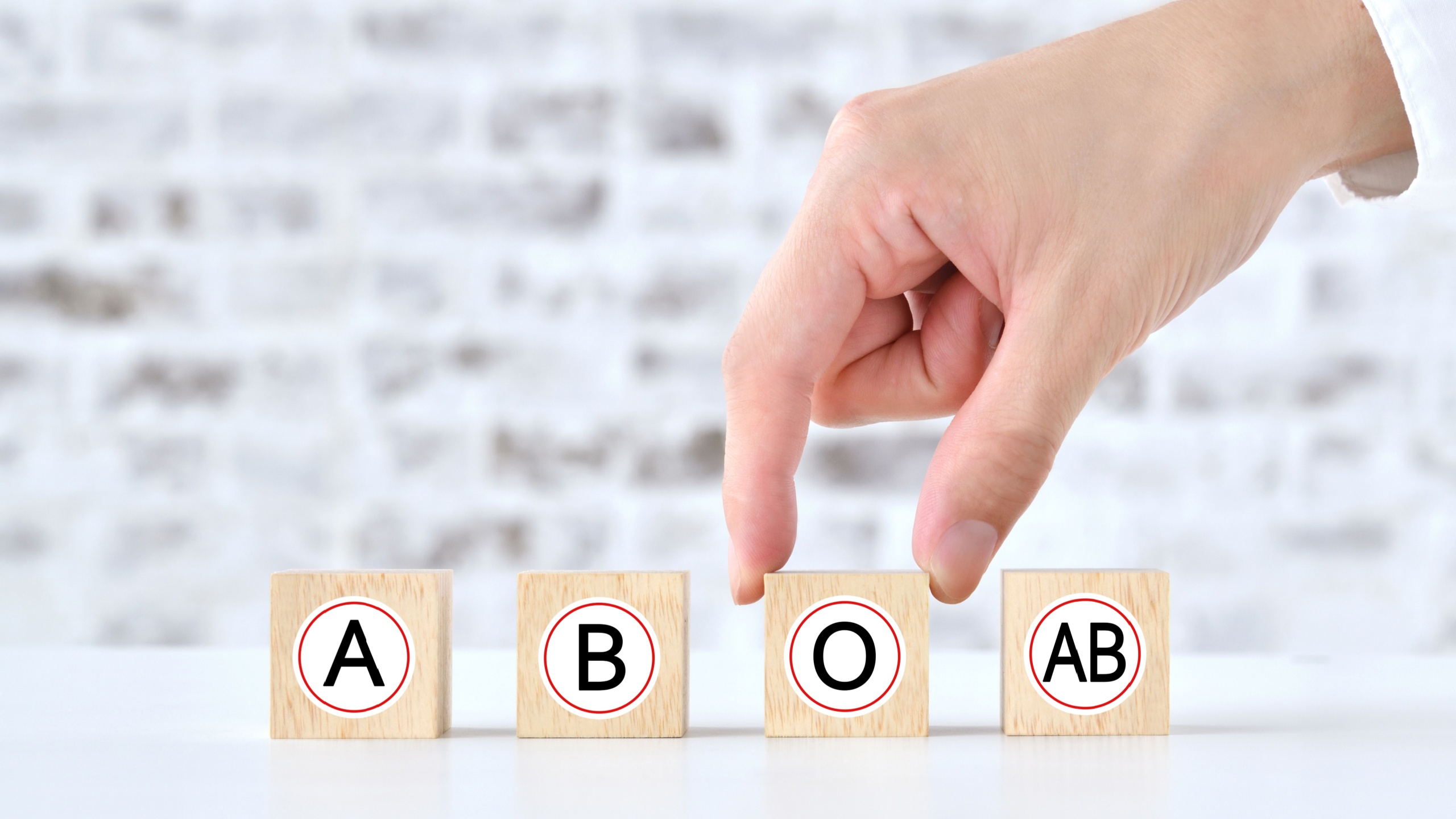 Human' s hand picking up wooden blocks with blood types alphabet