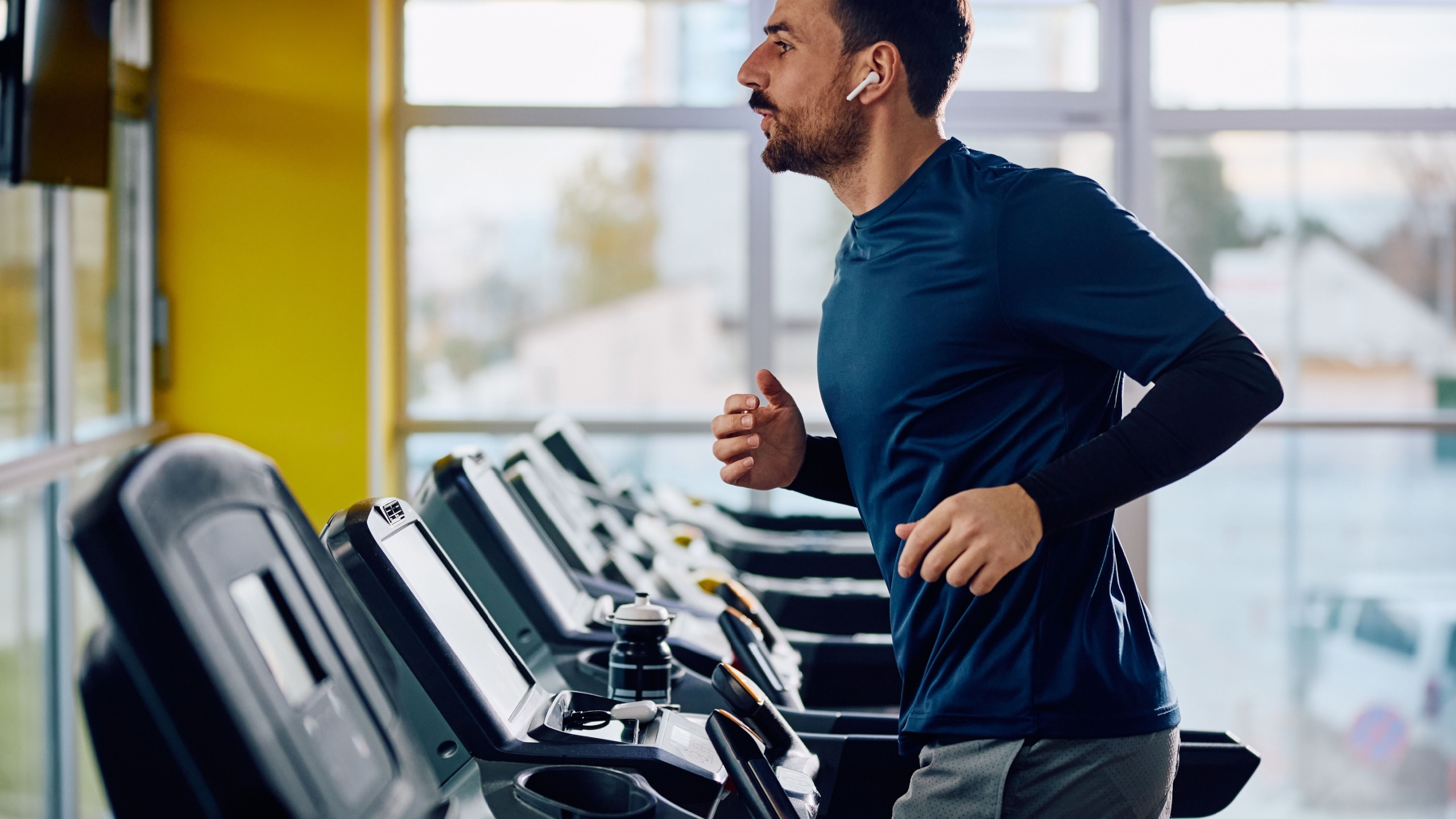 Male athlete running in treadmill during sports training in a gym.