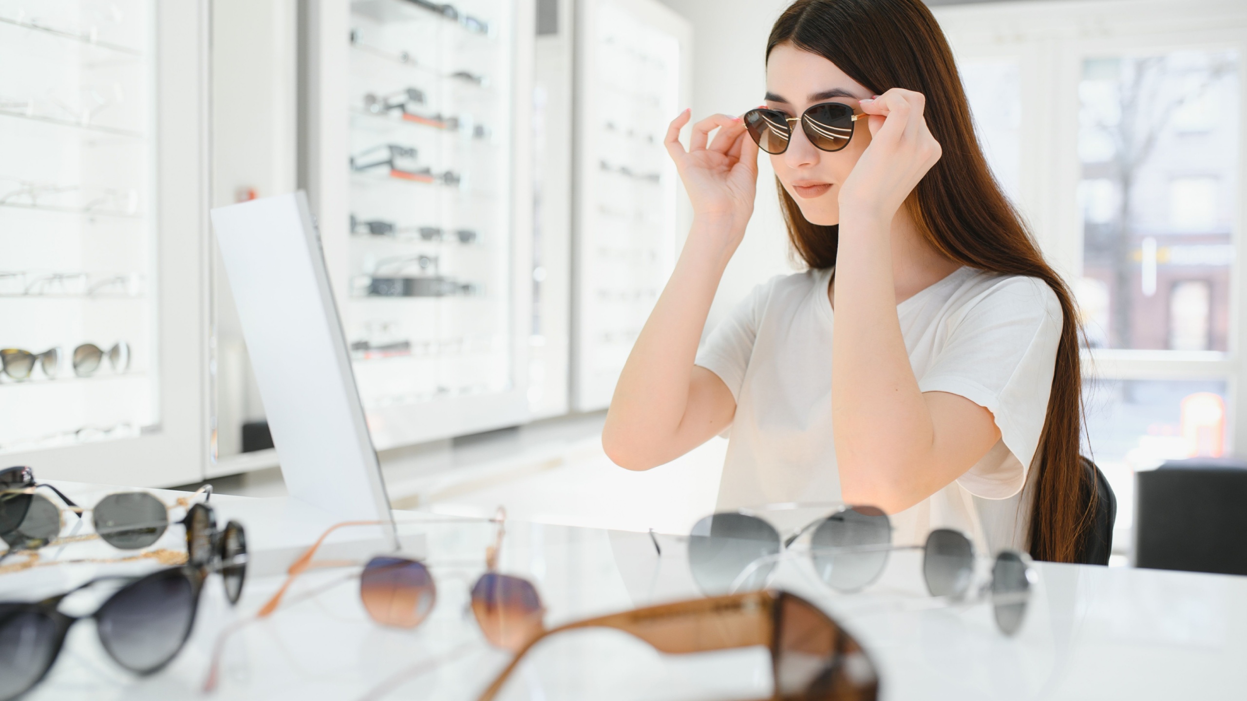 Happy Woman Wearing Sunglasses in a Optical Store. Cheerful girl trying trendy shades on sale.