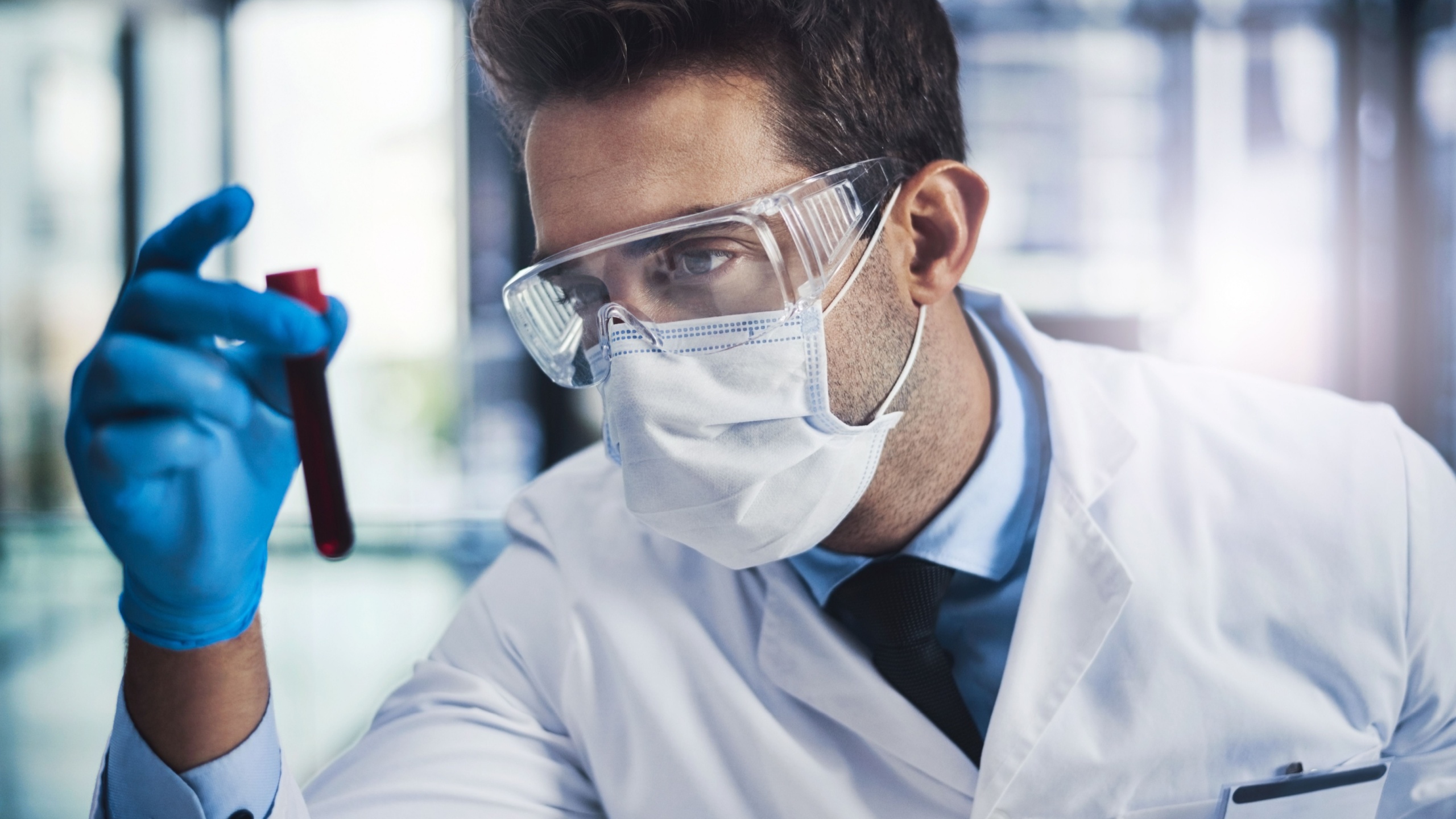 Scientist, man and check blood test at lab for medical virus, study dna and drug development. Male person, face mask and vial with genes engineering, clinical research and healthcare for vaccine cure