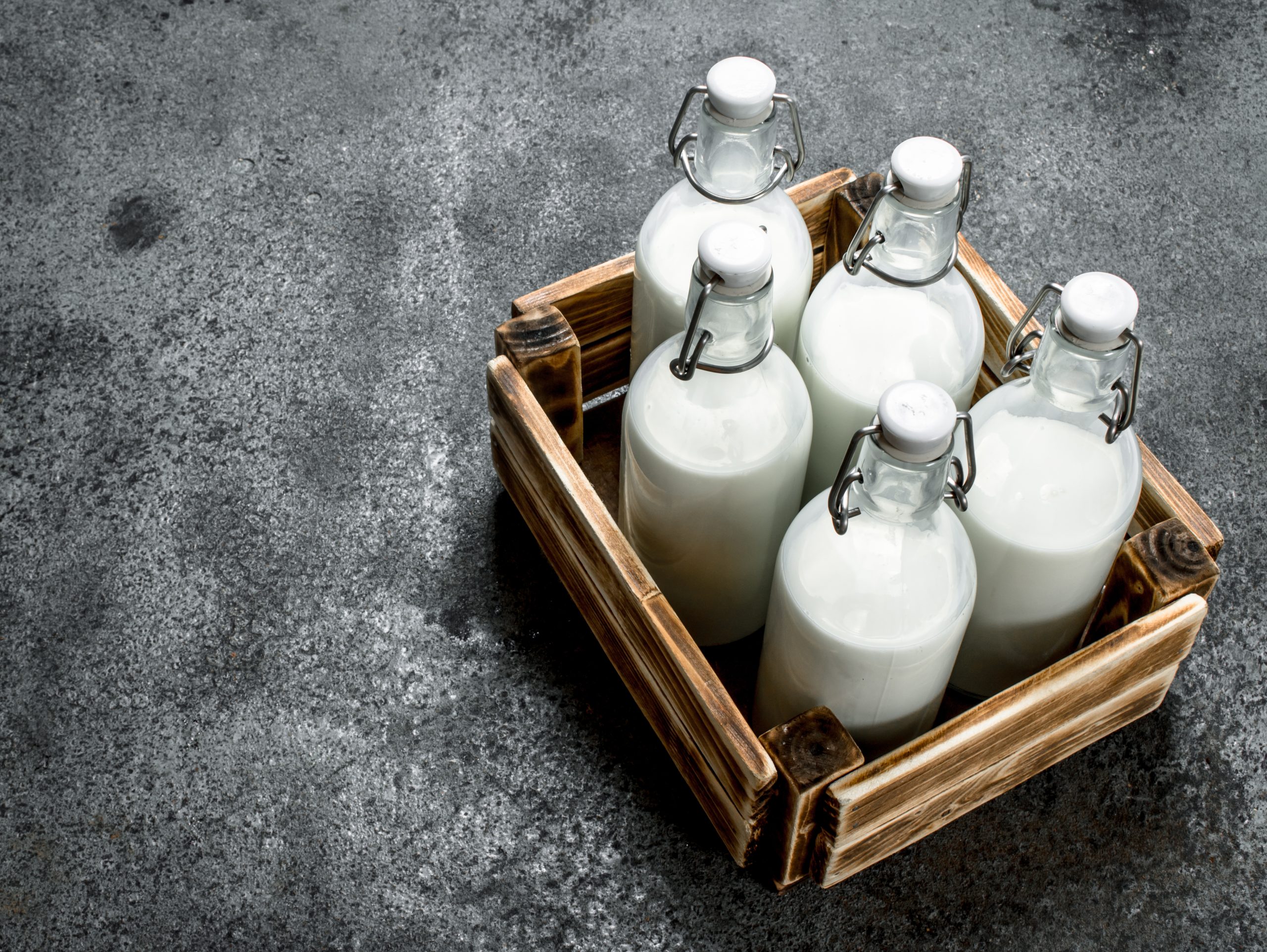 Bottles of fresh milk in an old box. On a rustic background.