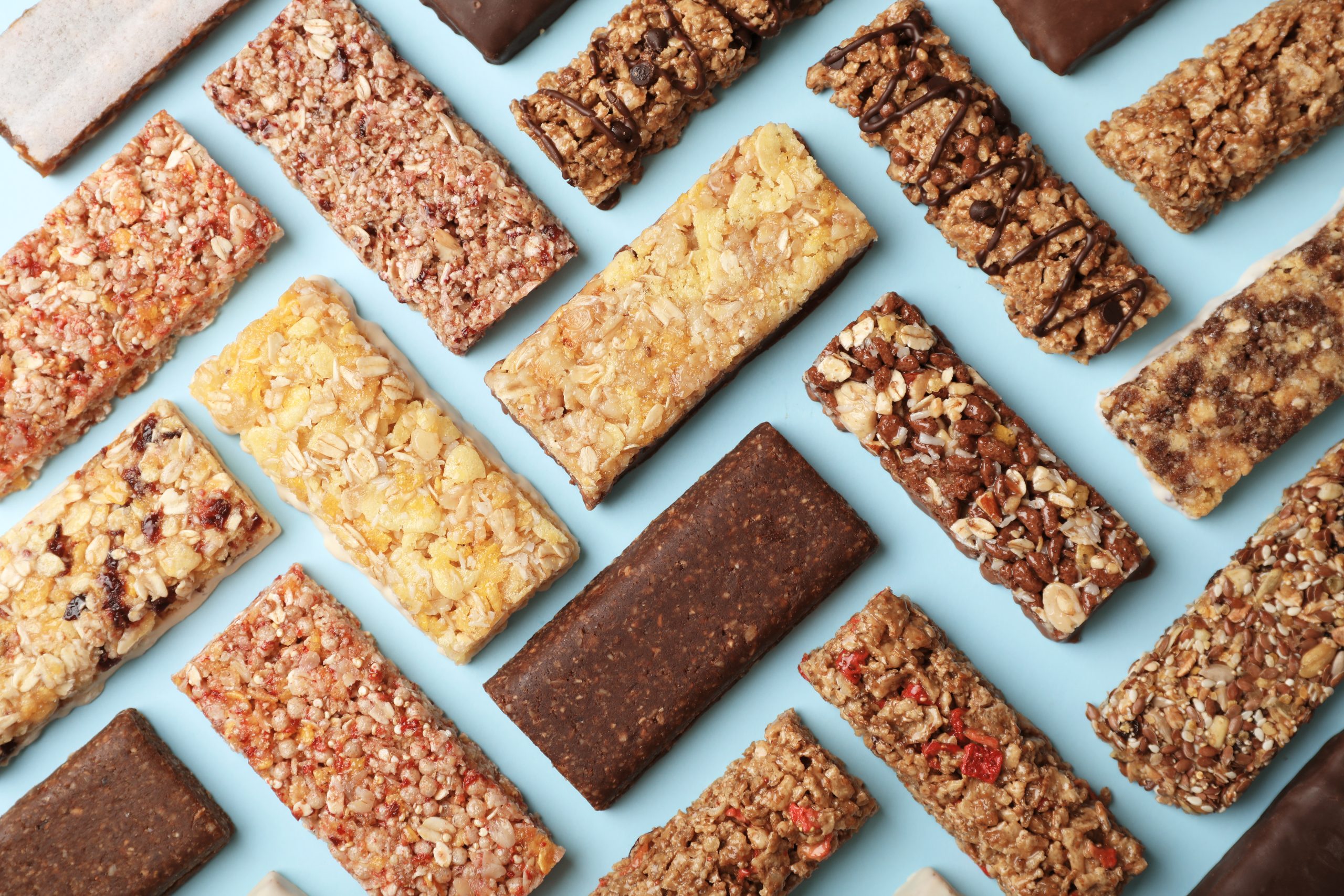 Flat lay composition with protein bars on color background
