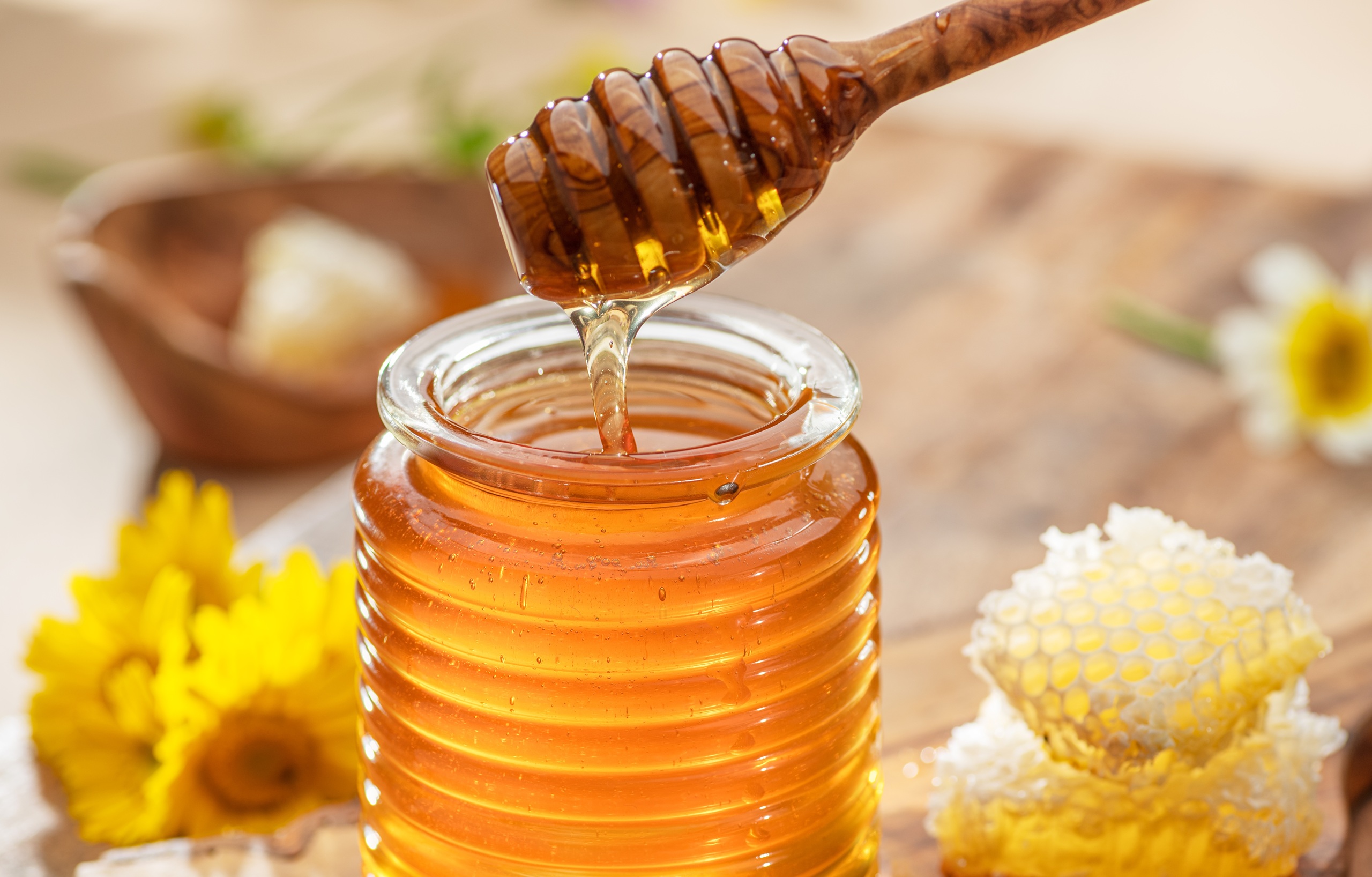 Natural organic honey in glass jar, honey dipper and honeycombs are near. Natural food background.