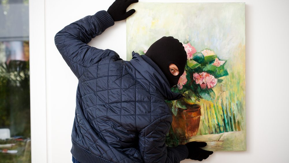 Thief stealing the piece of art from gallery of art.