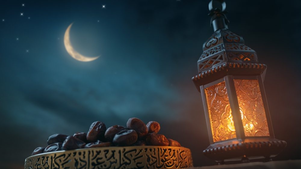 Ornamental Arabic lantern with burning candle glowing at night. Festive greeting card, invitation for Muslim holy month Ramadan Kareem.